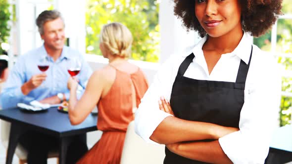 Portrait of smiling waitress standing with arm crossed