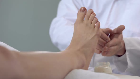 Specialist Doing Feet Massage Using Cream, Cosmetology Procedures, Beauty Salon