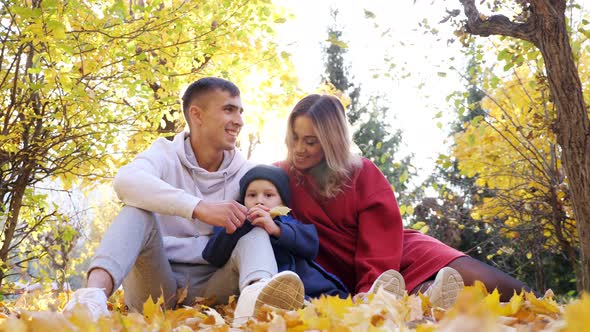 Mother Father and Son Spend Time Sitting on Yellow Leaves