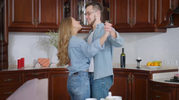 Romantic Loving Millennial Couple Dancing in Kitchen at Home
