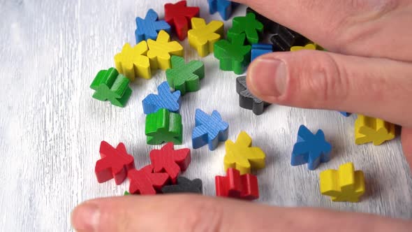 Hands take multicolored wooden figures on the board closeup. 