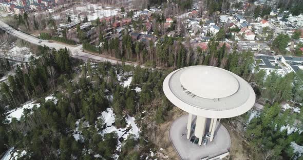 Aerial shot of a water tower during Winter. The shot cranes down while tilting up to reveal the land