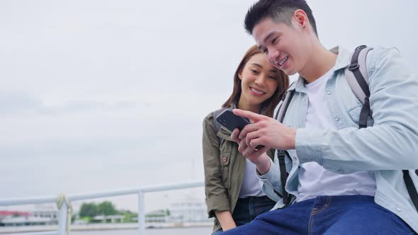 Asian attractive romantic couple sit on ferry and use mobile phone on vacation for honeymoon trip