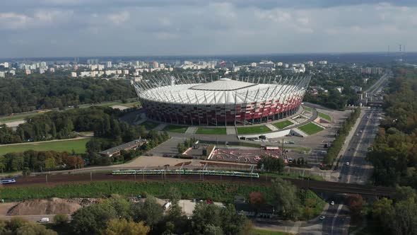 Panoramic Aerial drone view of The PGE Narodowy National Stadium with trains passing in the foregrou