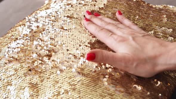 Gold sequins pillow. Touches a shiny textured surface.