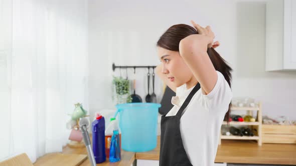 Portrait of Asian young woman worker tying hair before doing housework.