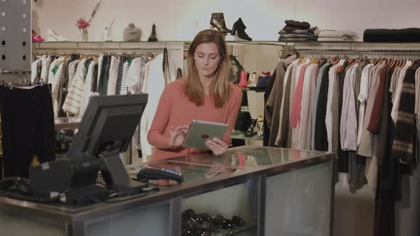 Small business owner in clothes shop working on digital tablet