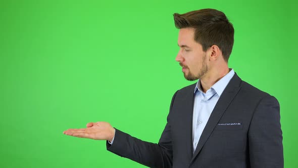 A Young Businessman Talks To the Camera, Puts Out a Hand with a Product and Continues Talking