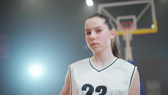 Slow Motion Portrait of a Young Female Basketball Player Holding a Ball in Her Hands and Looking at