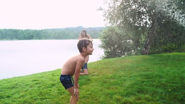 Mom Dad and Two Sons in the Summer on the Grass Poured Water From a Hose for the Lawn