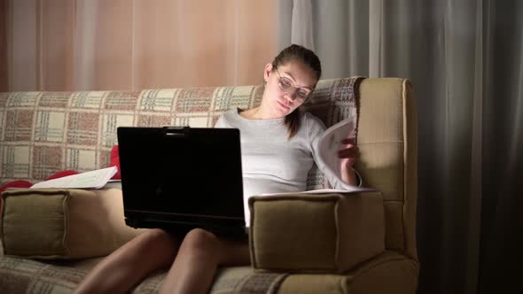 The camera zooms in on a young pregnant woman working at her computer at home