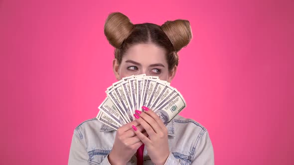 Teenager Holds Paper Bills and Winks. Pink Background. Slow Motion