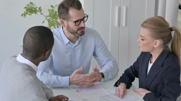 Businessman Talking to Male and Female Colleagues in Office