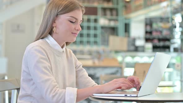 Young Woman Working on Laptop in Cafe