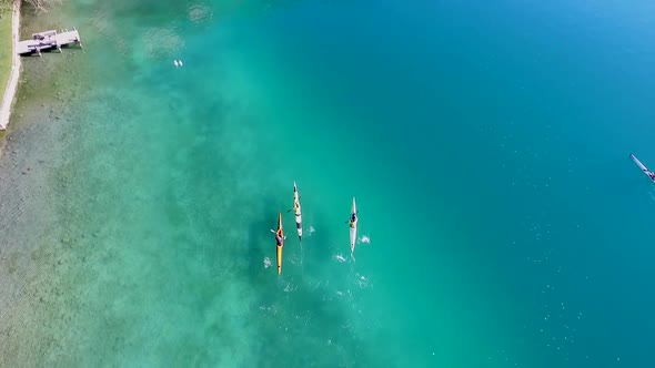 Three kayakers paddle in a scenic mountain lake.