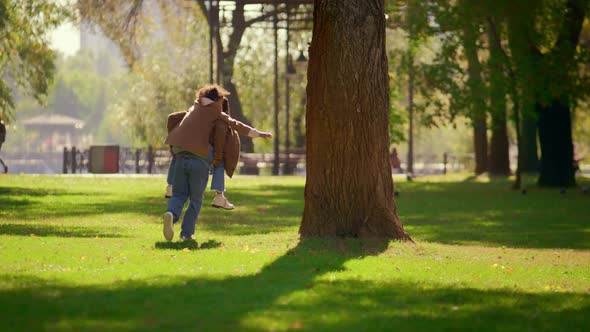 Happy Parent Piggybacking Daughter in Sunny Spring Park