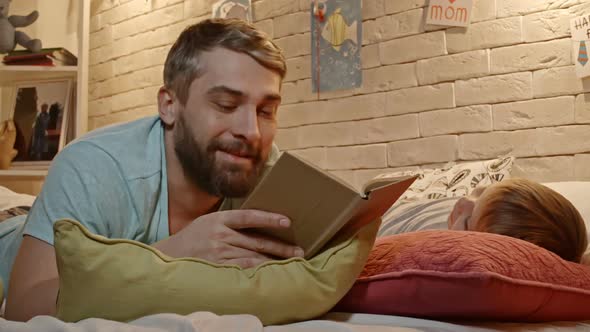 Dad Reading to Little Son in Bed
