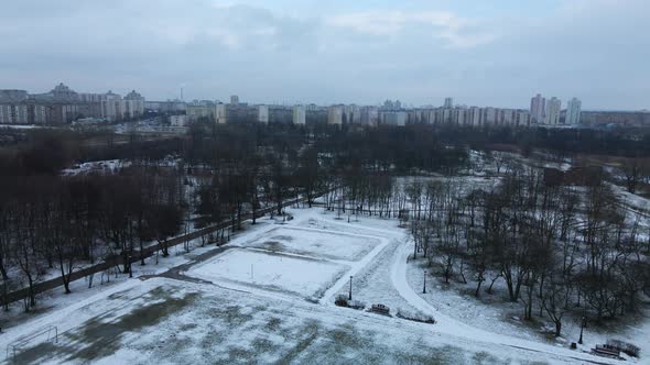 Flying over a sports field in a snow-covered city park. Aerial photography