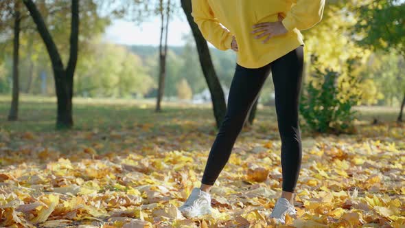 Girl Warming Up and Stretching Before Morning Run at the Park in Autumn