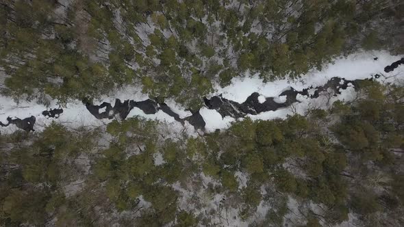 Horizontal top down aerial shot of snowy river in winter