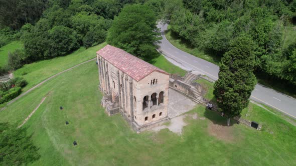 Aerial view of Santa Maria del Naranco aged catholic church with tourists visiting it.