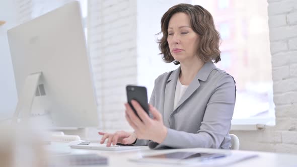 Creative Old Woman Using Smartphone and Computer