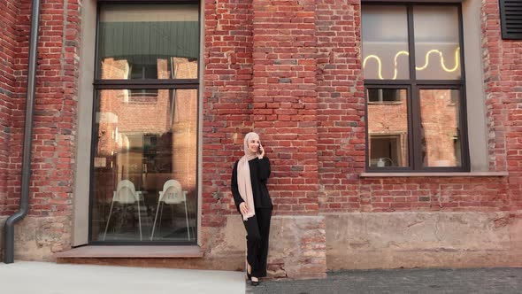 Cheerful Arabic Woman in Hijab Using Smart Phone Outdoor Standing Near Her Office Building