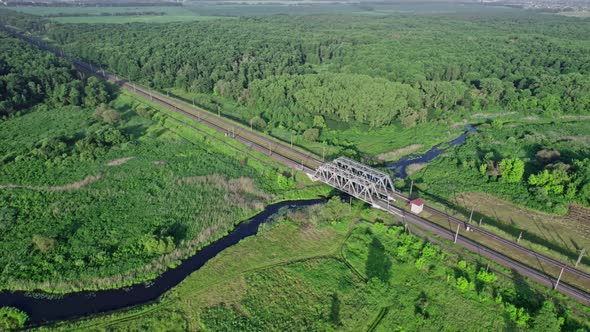 Metal Structure Railway Bridge Over a Small River and the Trees of a Forest