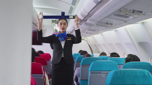 Asian flight attendant explaining and show safety demonstration on airplane before take off.