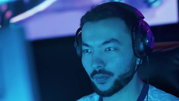 Portrait of a Young Man Gamer in Headphones Plays a Video Game Cyber Sportsman at the Game Blue Team