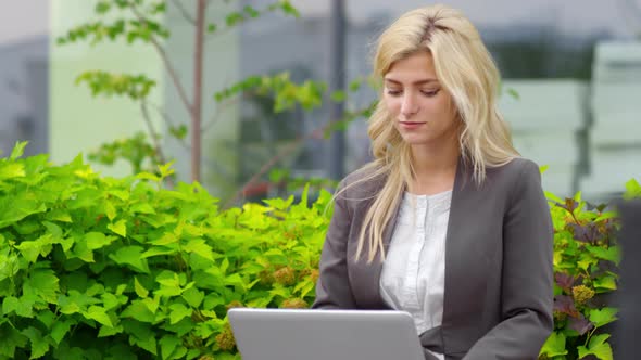 Blonde Businesswoman Working Remotely in Park