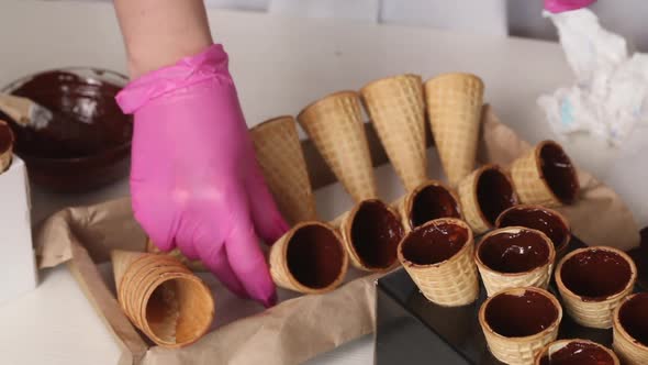 Wafer Cones Smeared With Liquid Chocolate. The Woman Puts Them On The Rack