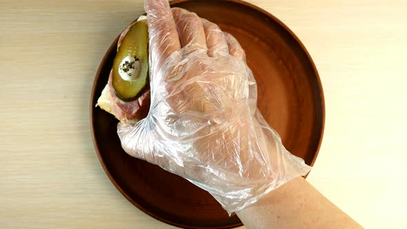 Human Hand Put Sandwiches with Sausage and Pickled Cucumber on Round Dish.