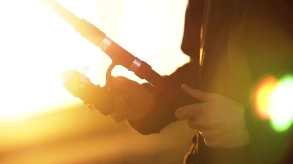 Fisherman's Hands Twist Fishing Rod in Bright Warm Sunset.