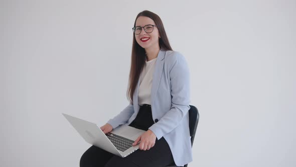 A Successful Young Business Lady Sits on Her Lap with a Laptop and Laughs Contagiously