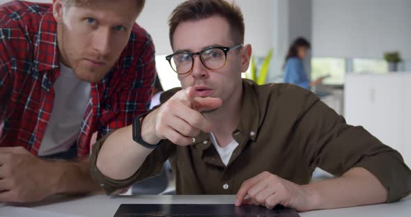 Two Concentrated Employees Working on Laptop Together