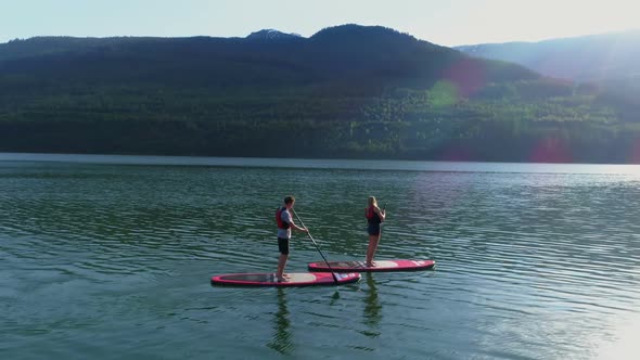 Couple on stand up paddle board oaring in river 4k