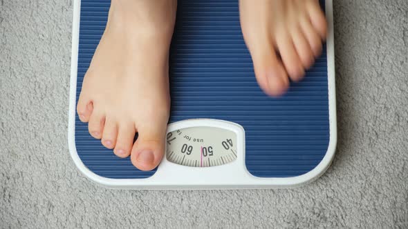 A Woman Stands on the Scales Her Legs Closeup the Measuring Tape Falls