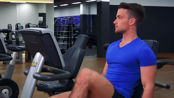 A Young Fit Man Trains on a Recumbent Bike in a Gym - Closeup