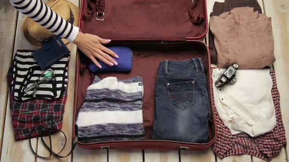 Woman Hand Packing Clothes and Gadgets in Suitcase Luggage for Travel