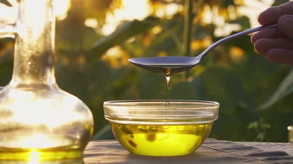 Spoon Scoops Up Vegetable Oil, The Oil Flows From The Spoon. Vegetable Oil In A Glass Bottle