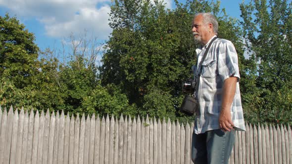 Retired Man with Camera on Neck Enjoys Walking Along Street