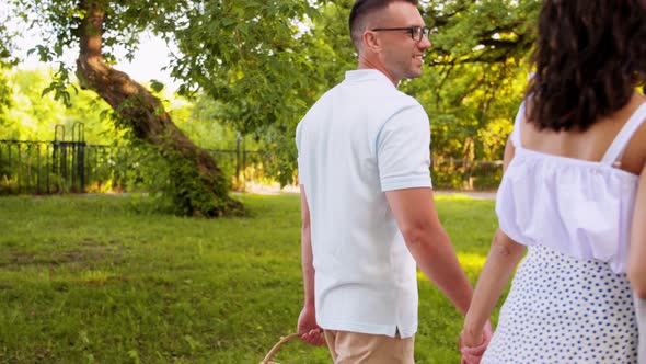 Happy Couple with Picnic Basket at Summer Park