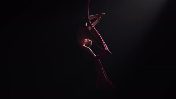 Young Female Circus Gymnast Spins Hanging Upside Down on Aerial Silk and Demonstrates Stretching