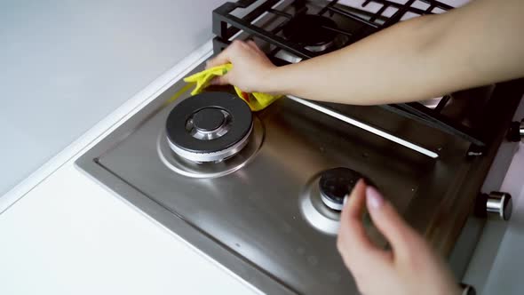 Cleaning kitchen gas stove. Womans hand cleaning gas stove with sponge