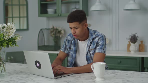 20s African American Male Freelancer Working Remotely at Home Sitting in Kitchen