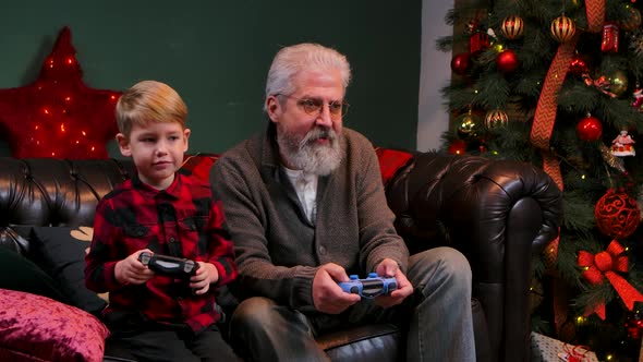 Happy Old Grandfather with Grandson Playing Game with Joysticks