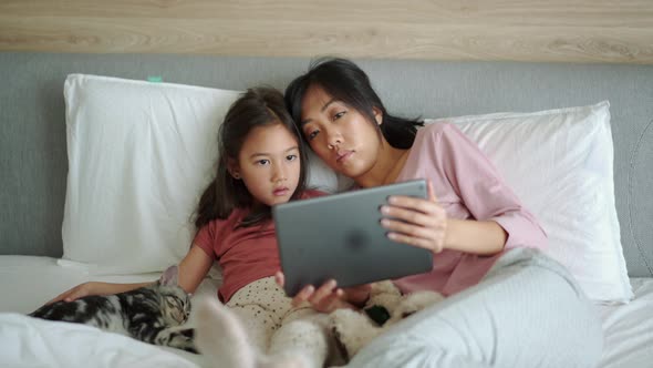 Confident Asian mother and daughter looking at the tablet