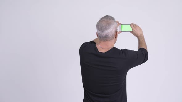 Rear View of Persian Man Taking Pictures with Phone