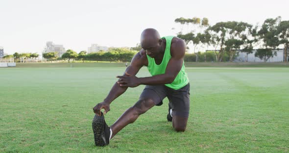 Fit african american man exercising outdoors, stretching